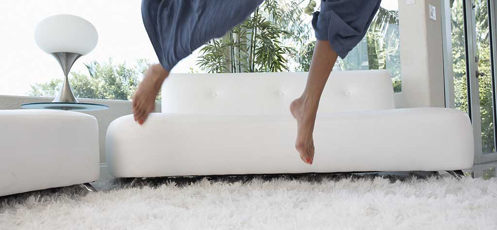Young woman jumping in room, low section (blurred motion)